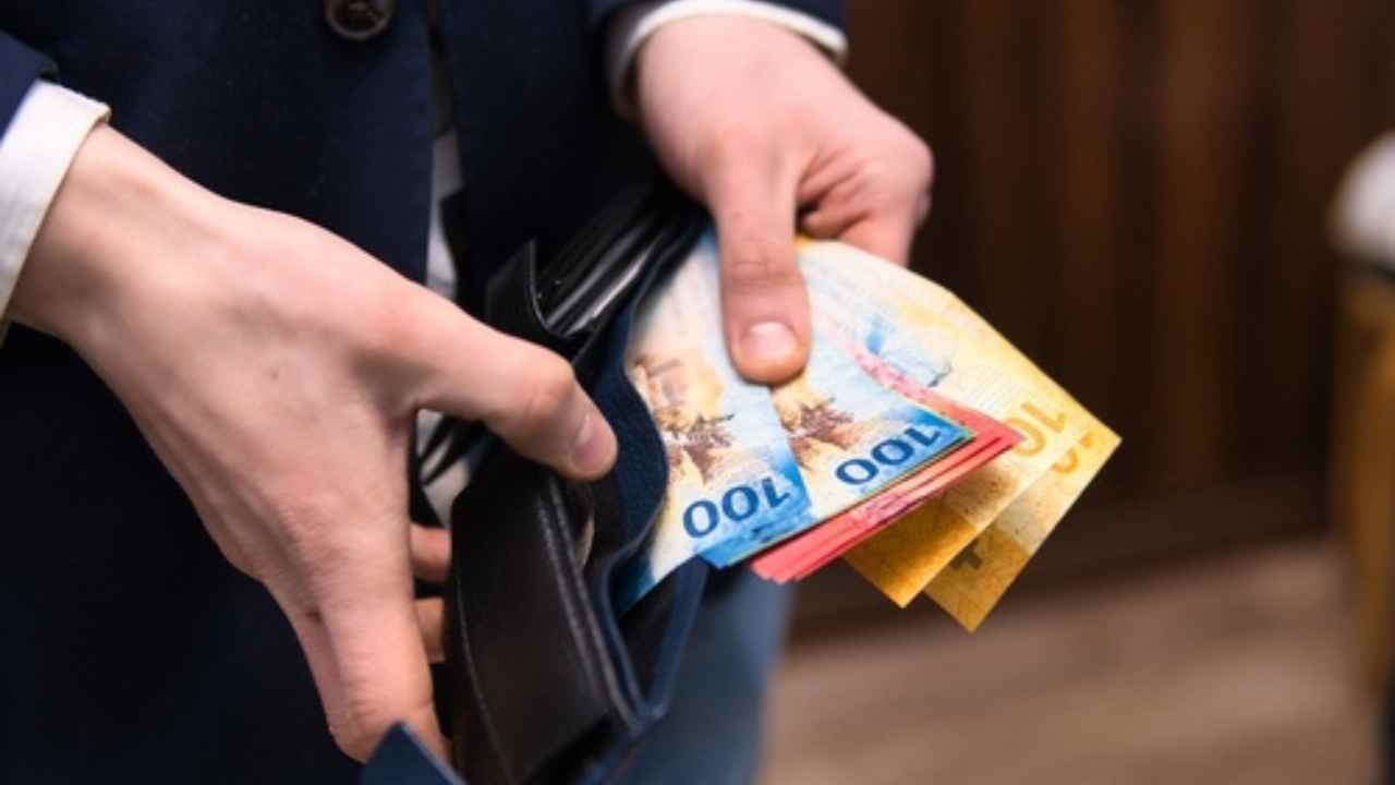 Homem segurando carteira com dinheiro