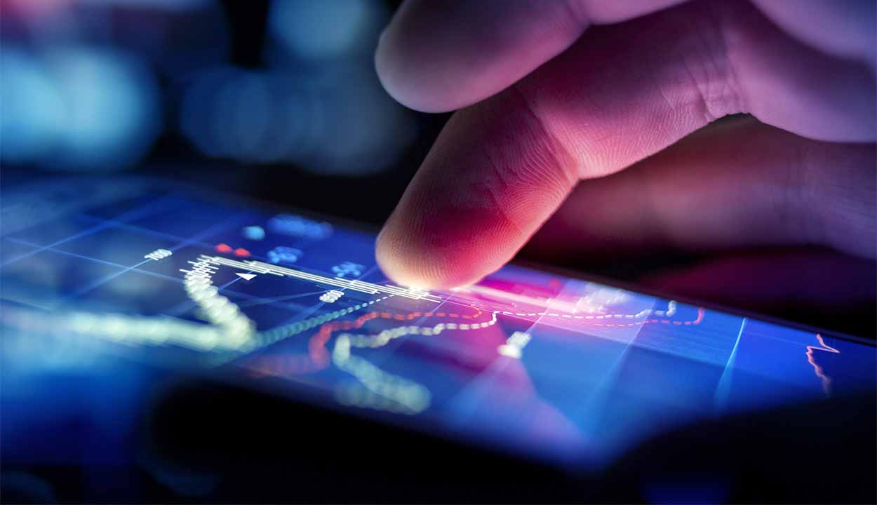celular na mão com gráficos do mercado de ações aparecendo na tela