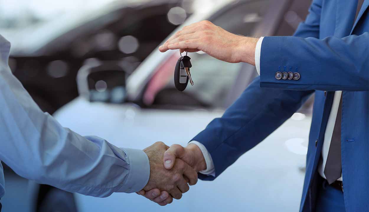 Homem segurando chave de carro e apertando mão de outra pessoa