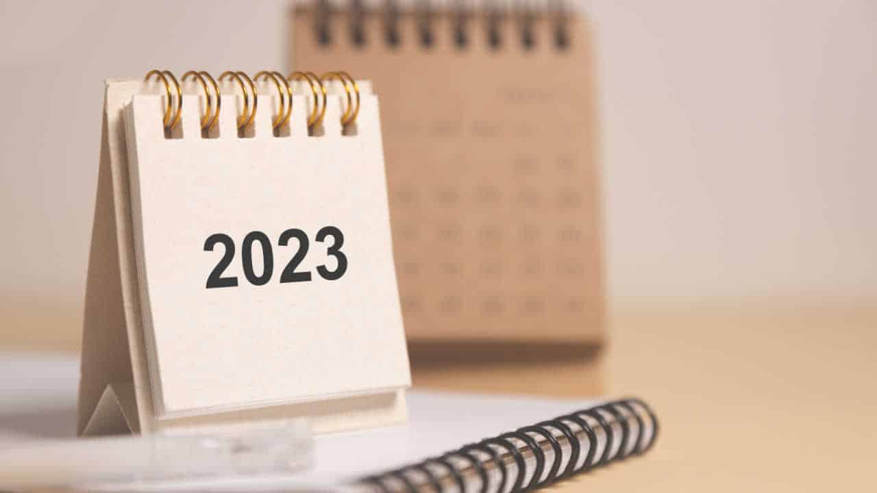 bloco de notas exibindo o ano 2023 com um calendário ao fundo