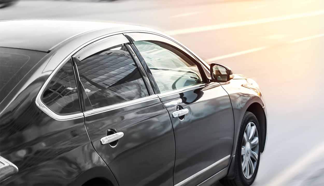 Carro preto, com vidros fechados, em movimento na estrada.