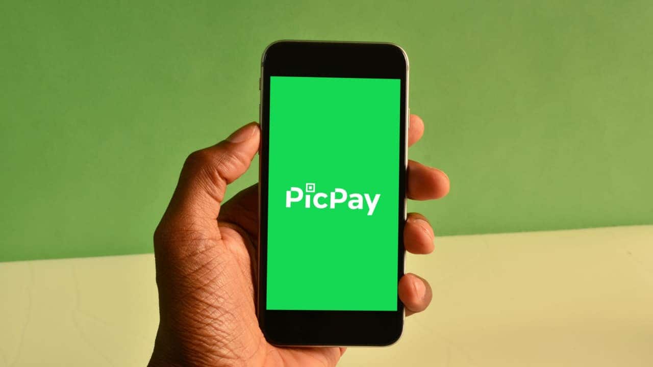 Mão segurando celular que exibe logo do PicPay