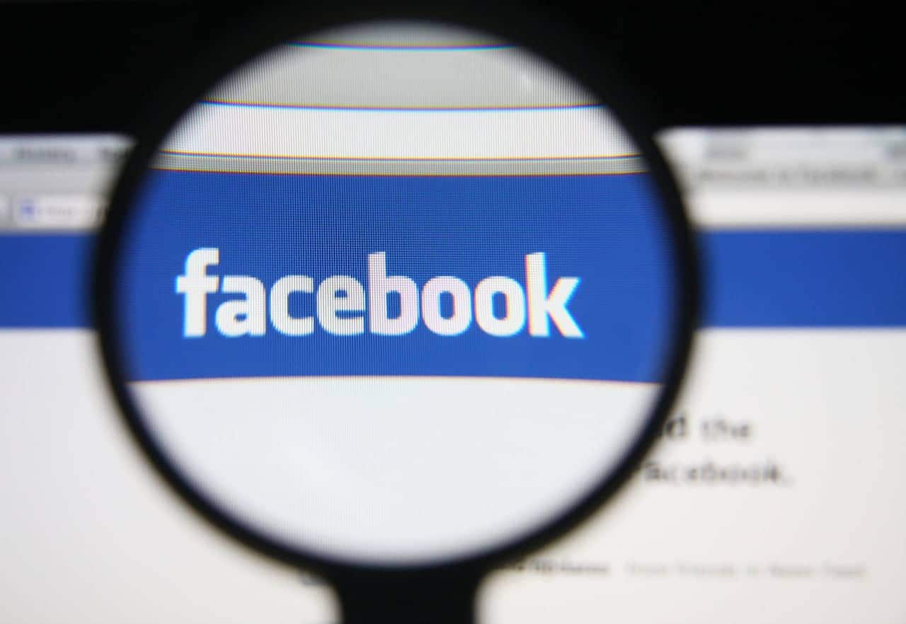 Imagem de um lupa focando na logo do Facebook