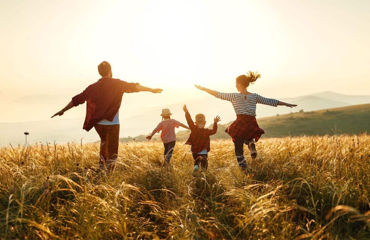 Família feliz correndo num campo