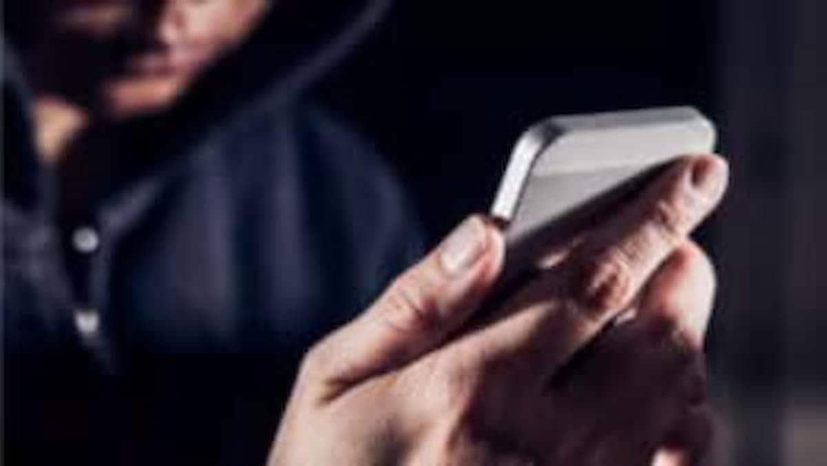 Homem encapuzado e suspeito segura um celular