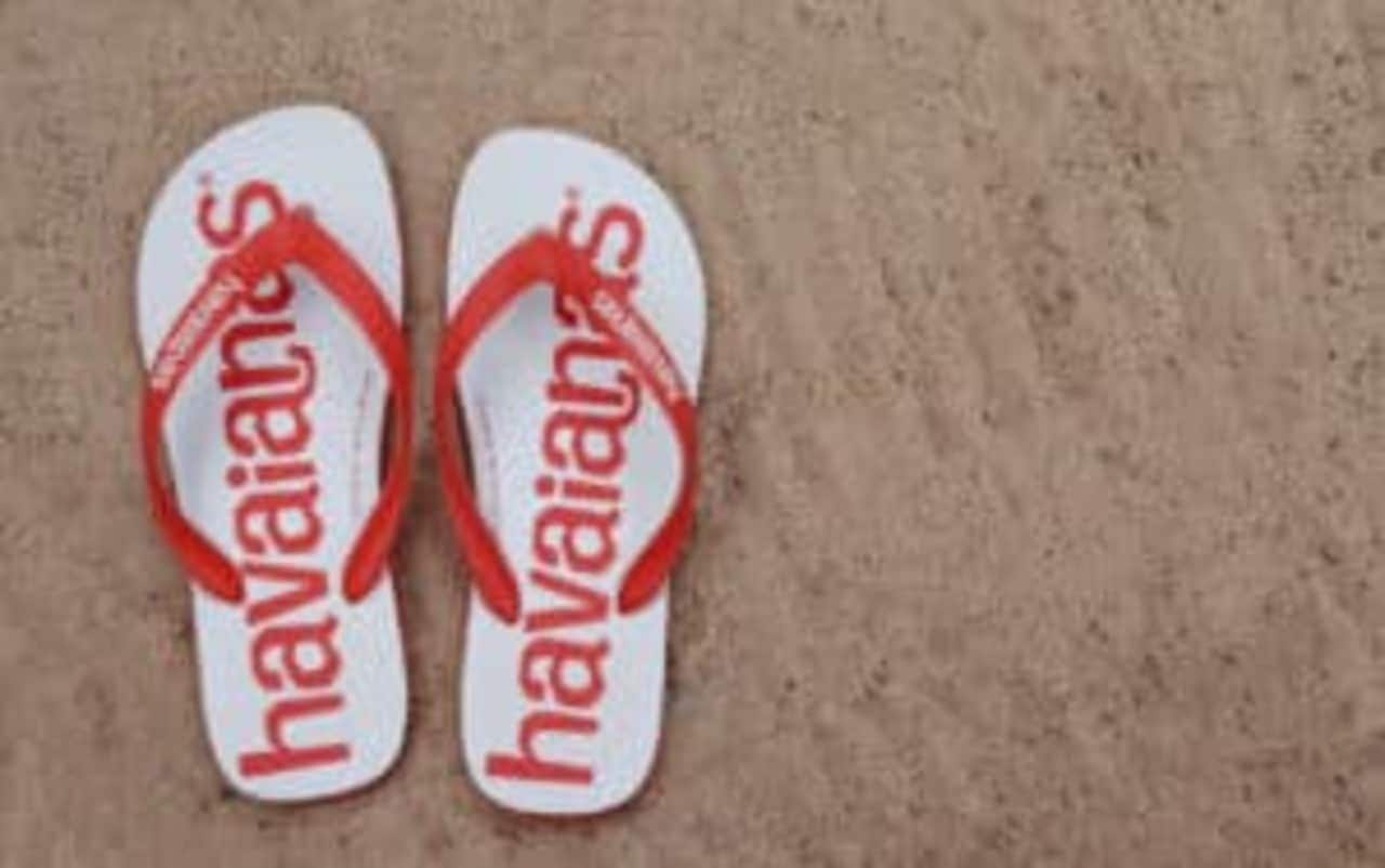 Par de chinelos Havainas branca e vermelha sobre a areia da praia