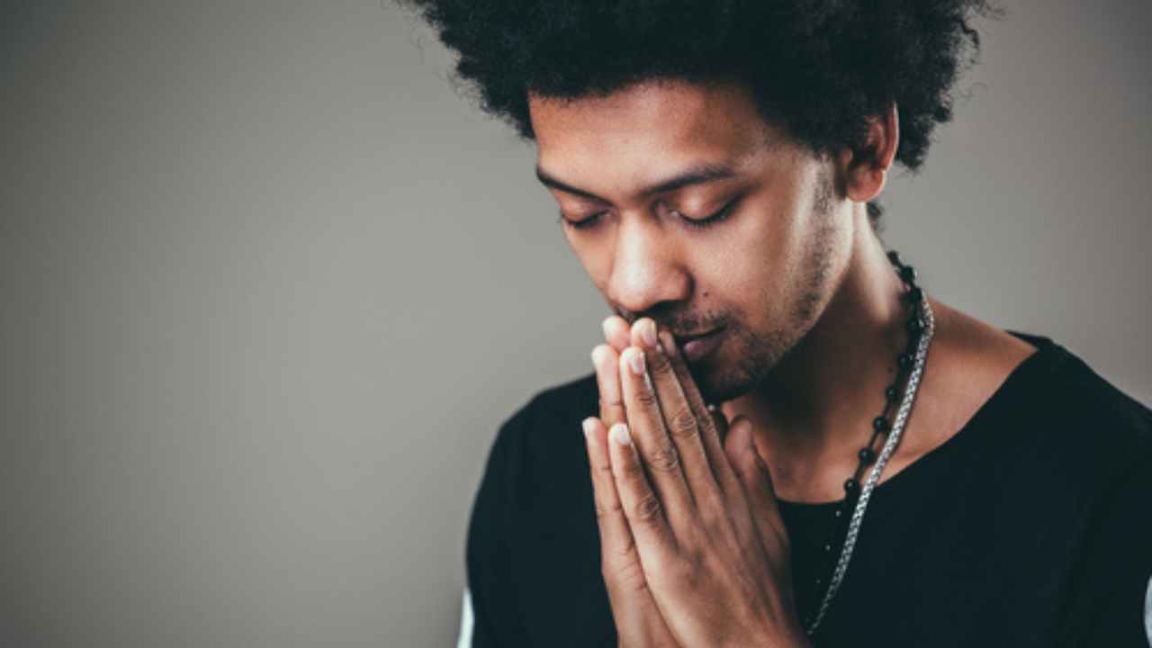 Homem negro com as mãos em reza