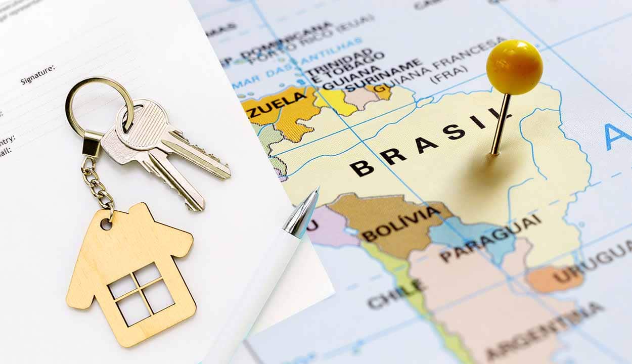 Mapa do Brasil espetado com um alfinete amarelo e papel com molho de chaves com chaveiro em formato de casa