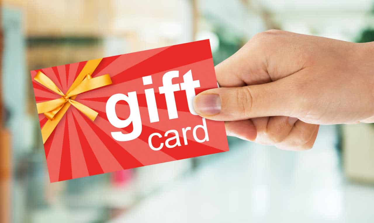 Mão segurando um gift card com o fundo desfocado