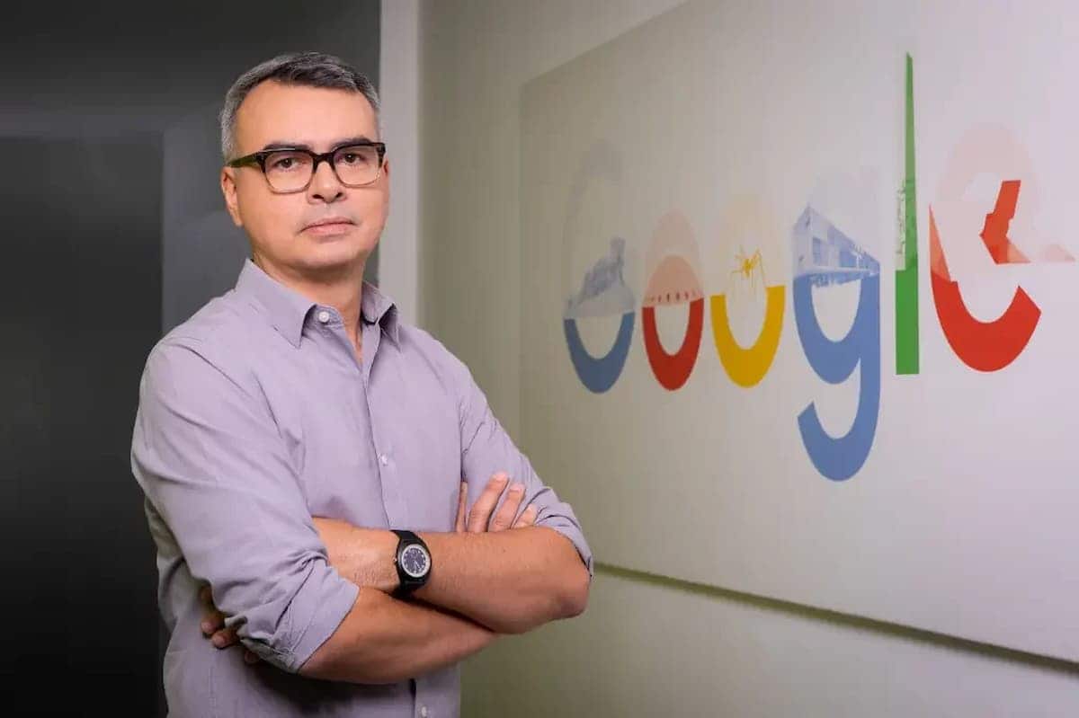 Diretor do Google, Marcelo Lacerda, de perfil, ao lado dele está um quadro com a logo do Google.