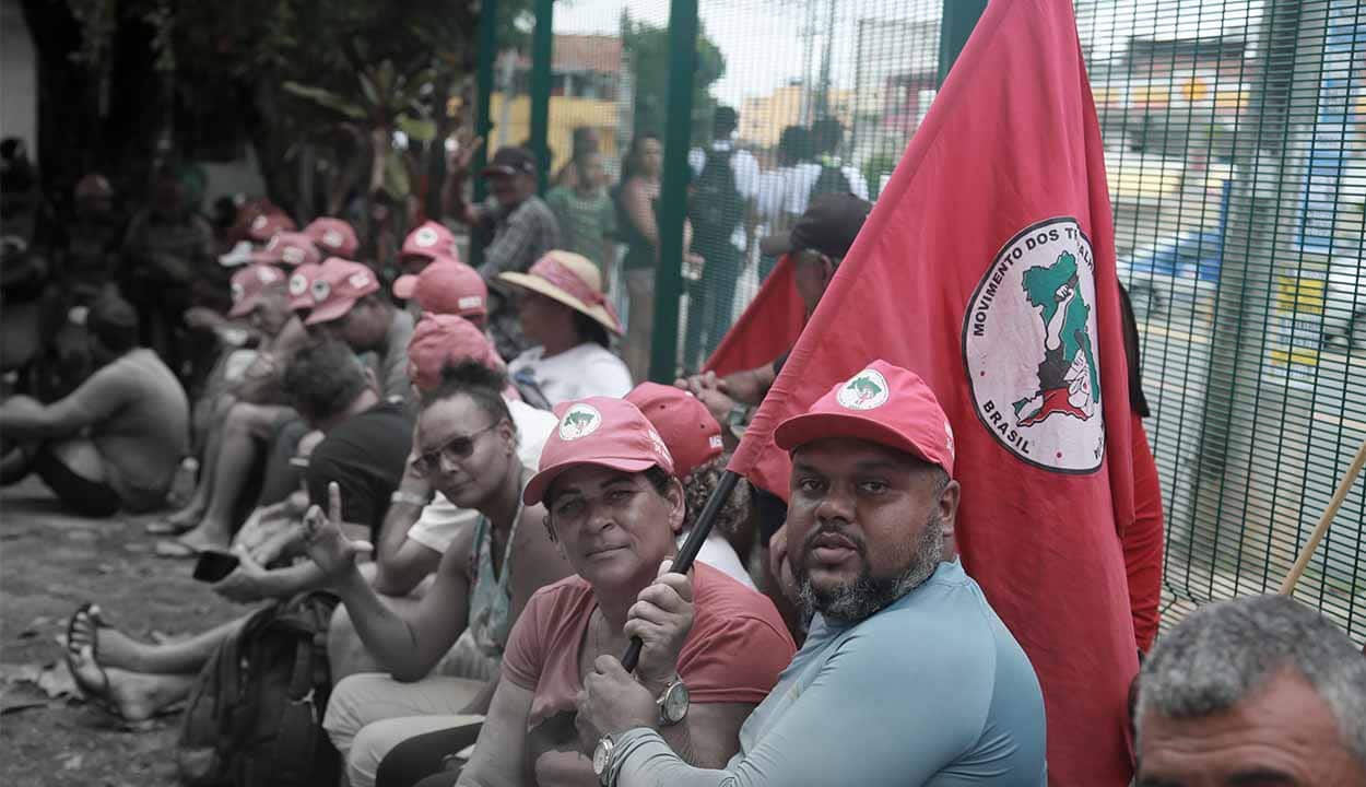 manifestantes do MST com bonés e bandeiras do movimento
