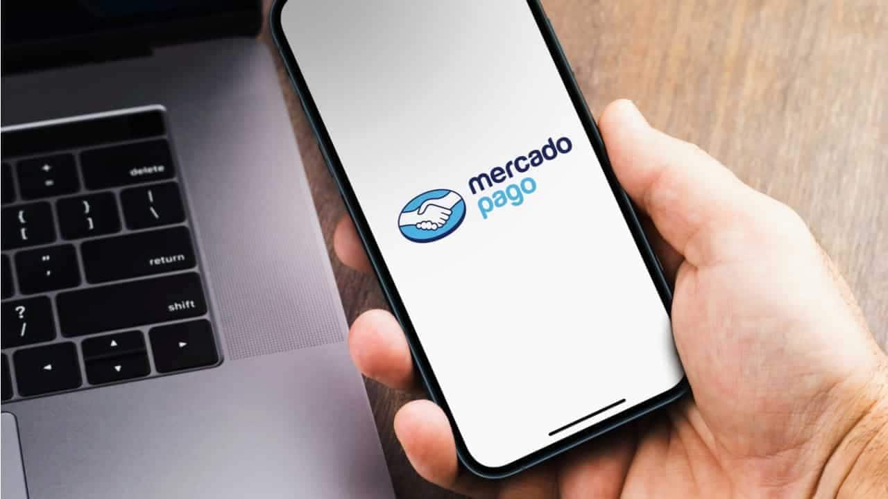 Homem segurando smartphone com aplicativo do Mercado Pago