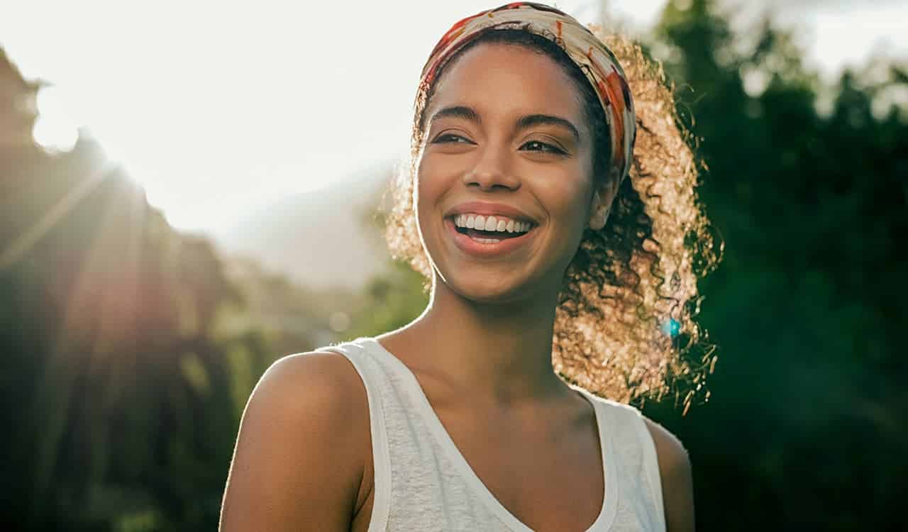imagem de mulher negra sorrindo ao ar livre