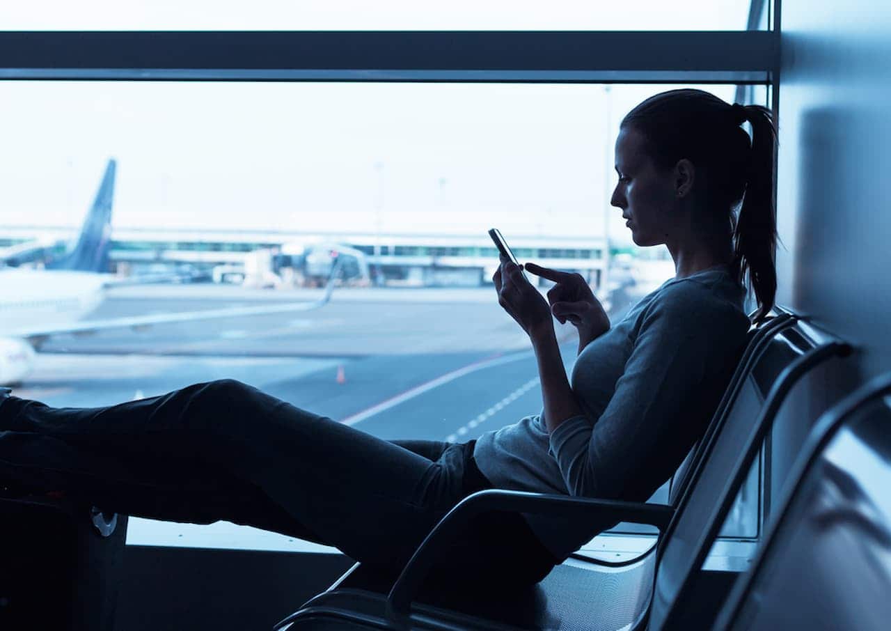 Mulher usando seu celular no aeroporto.