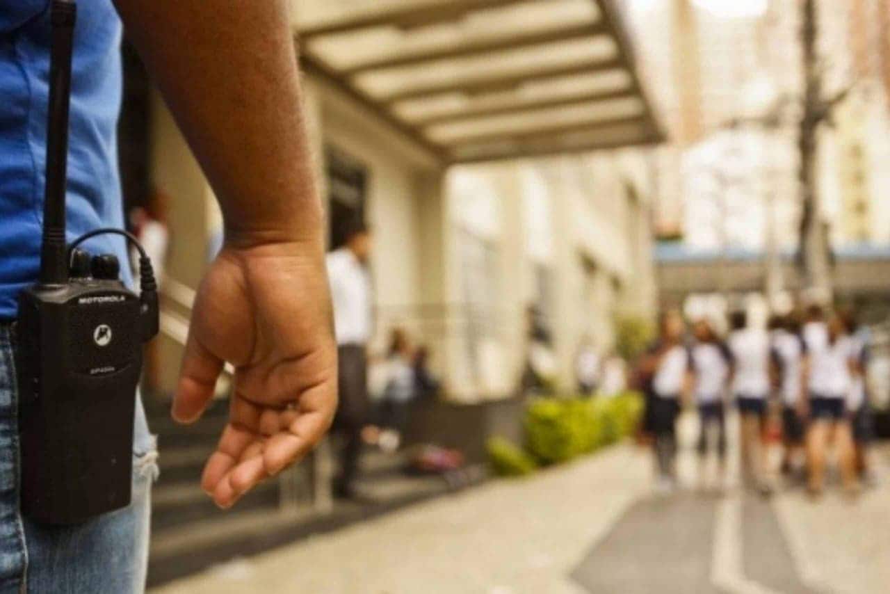 pessoa cuidando da segurança em escola com diversas crianças ao fundo