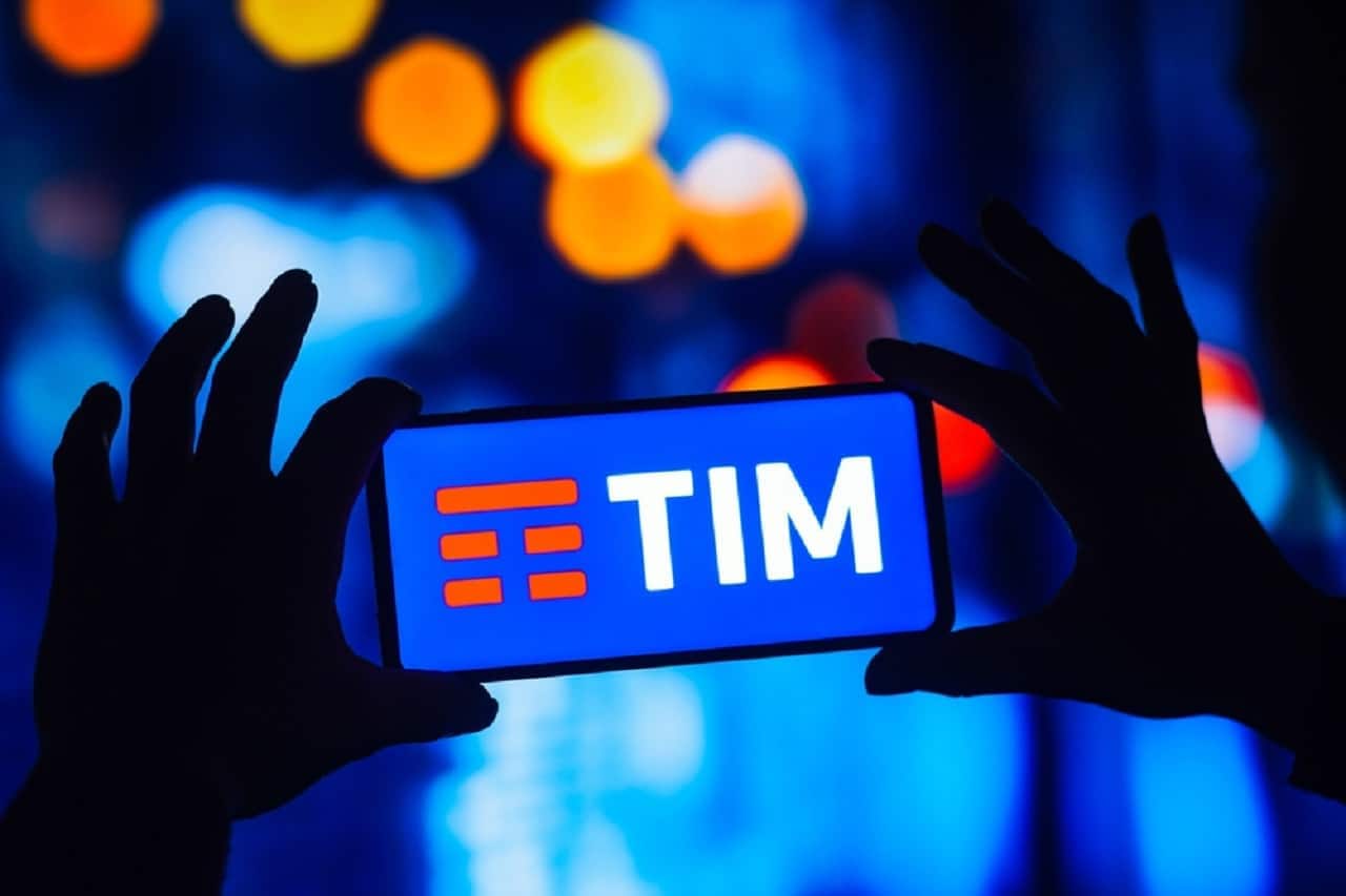 Imagem de duas mãos segurando um celular na horizontal, com a tela na TIM