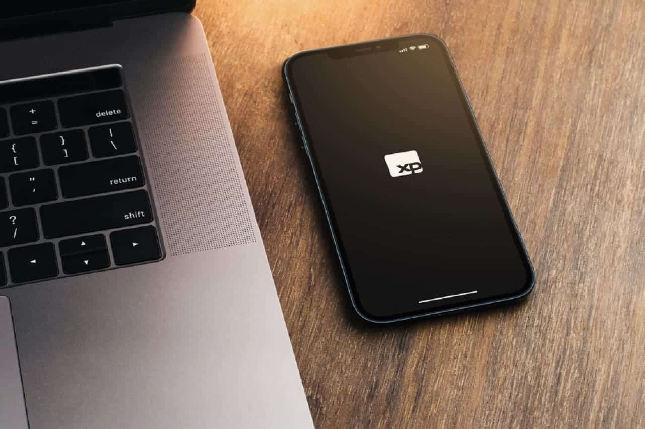 Imagem de um computado e um celular com a tela na logo da XP