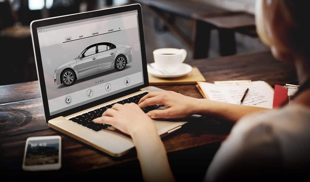 Pessoa mexendo no laptop. Ela está em um site escolhendo um carro para comprar.