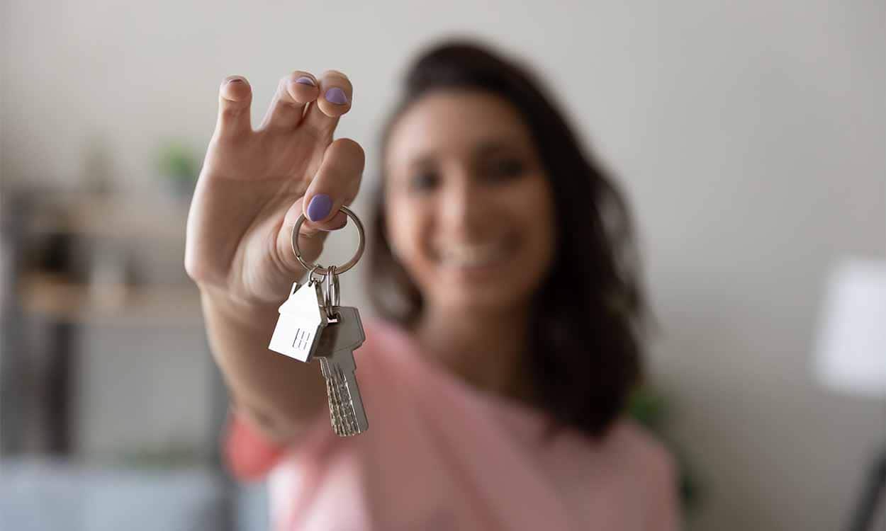 Imagem de mulher segurando uma chave de casa nova.