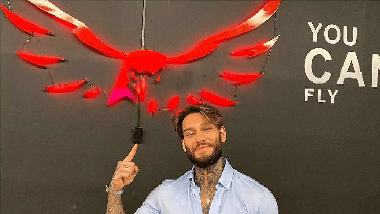 Imagem do cantor Lucas Lucco em sua academia apontando pro símbolo de falcão em vemelho