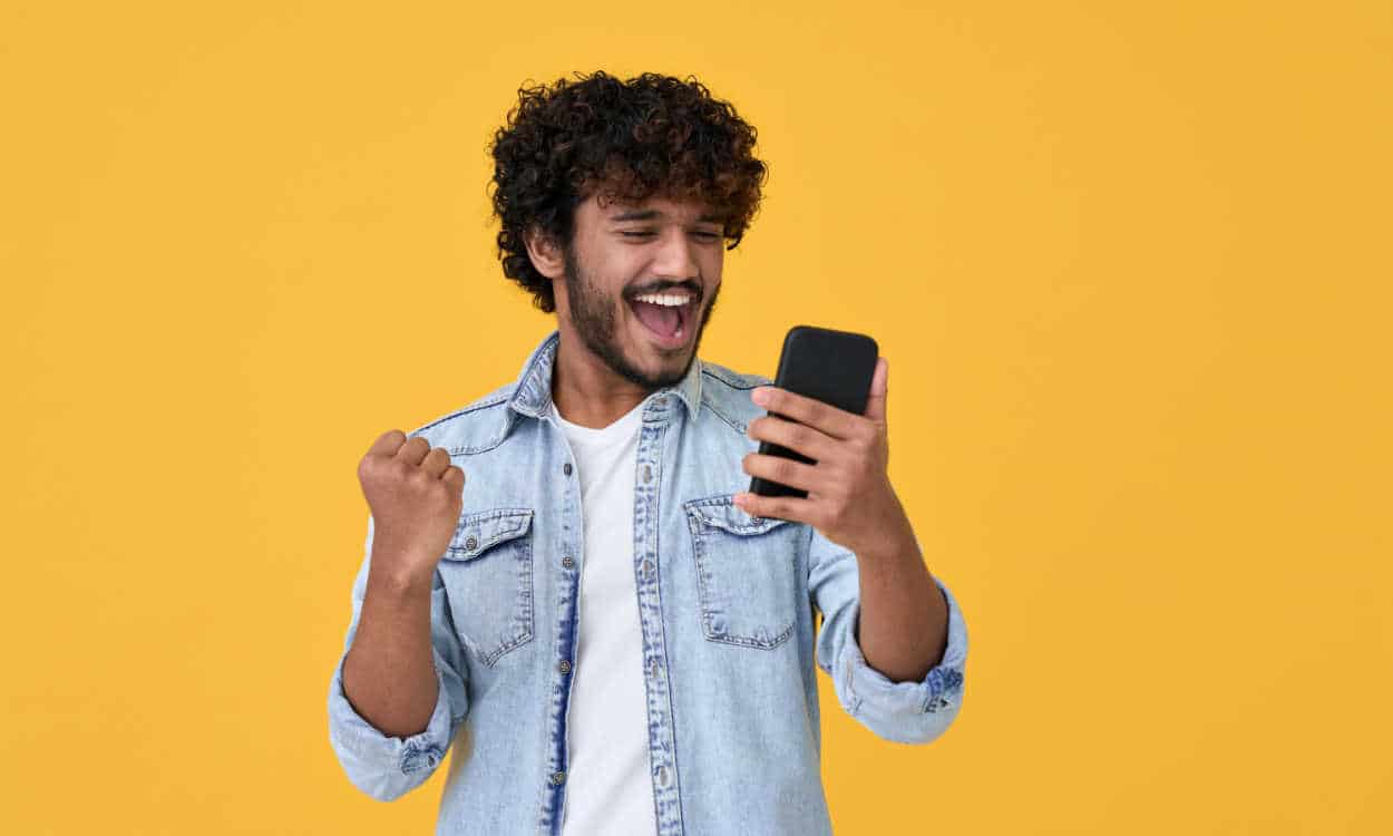 Pessoa comemorando enquanto olha para o celular
