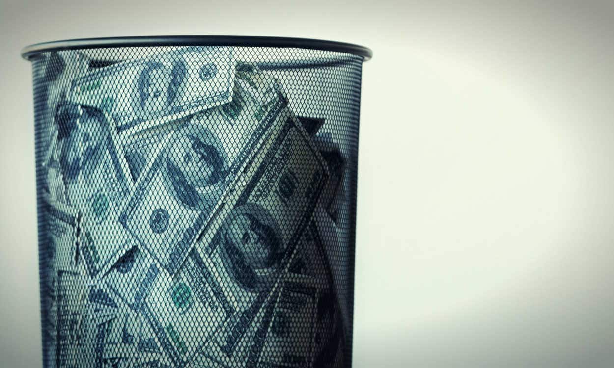 Cesta de lixo com várias notas de dólar
