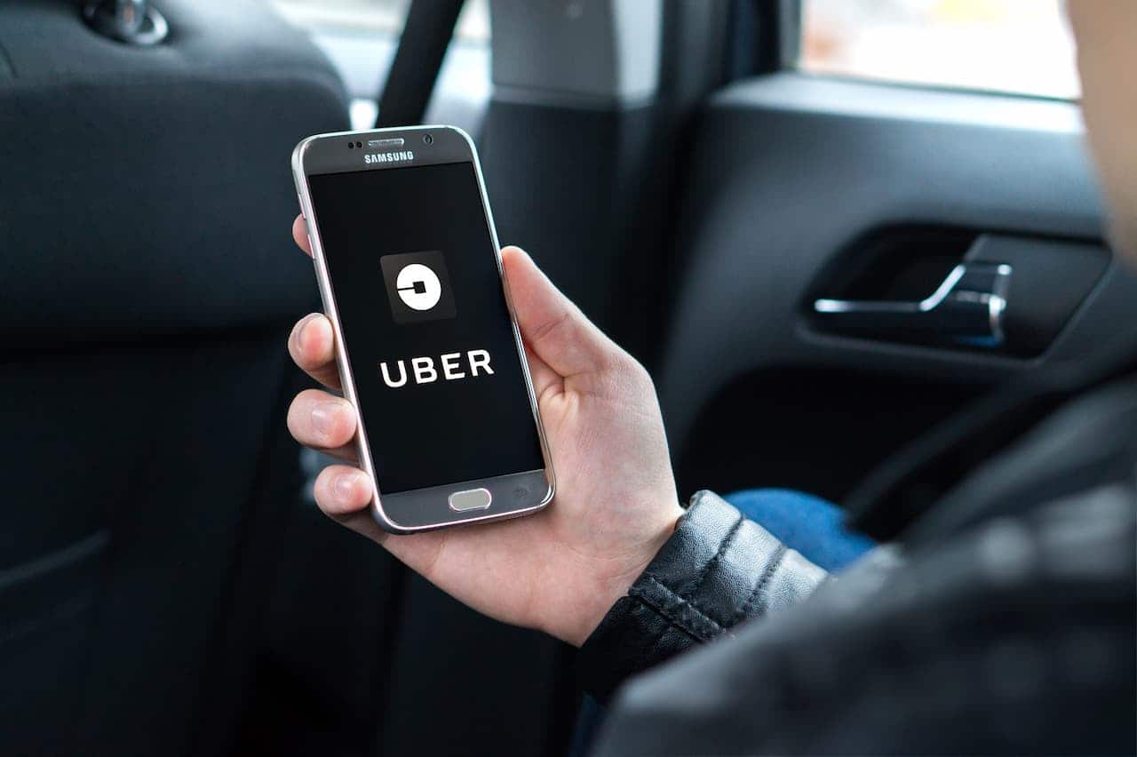 homem dentro de carro segurando celular com tela aberta no aplicativo da Uber