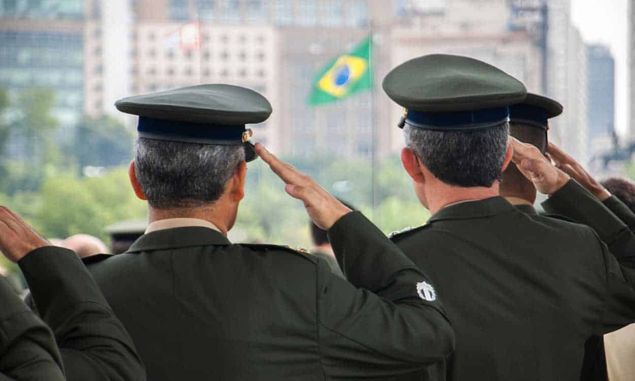 Oficiais do exército de batendo continencia para a bandeira do Brasil