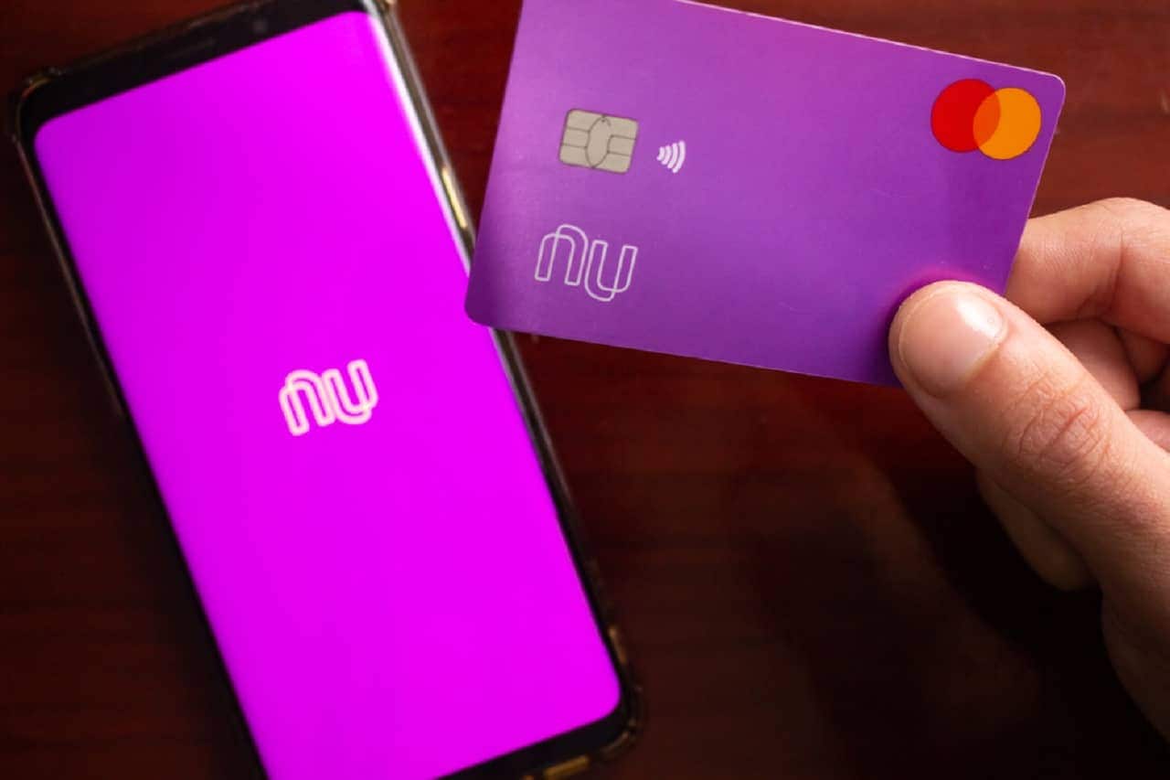 Imagem de um celular com a tela na logo do Nubank e um cartão do Nubank