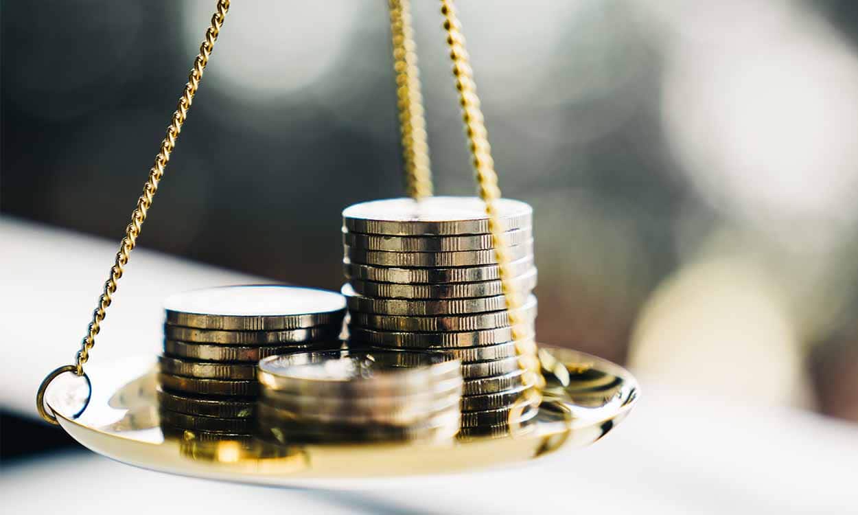 Balança dourada com moedas prateadas empilhadas em cima de seu prato
