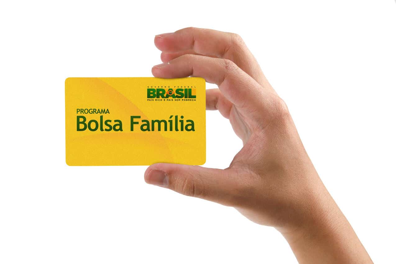 Mão segurando o cartão do Bolsa Família