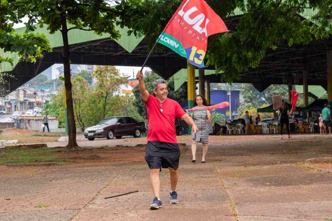 Homem segurando a bandeira do Partido dos Trabalhadores (PT) na campanha do Lula
