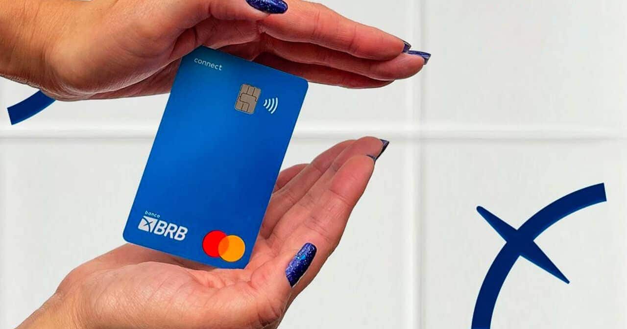Mãos femininas segurando cartão BRB (bandeira Mastercard)