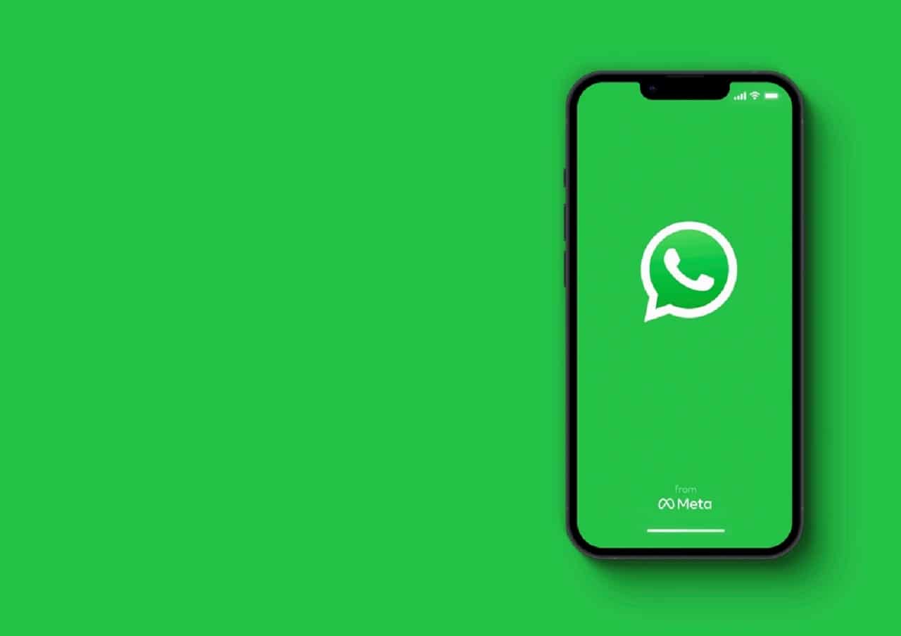 Imagem de um celular com a tela na logo do WhatsApp. O fundo da imagem é verde