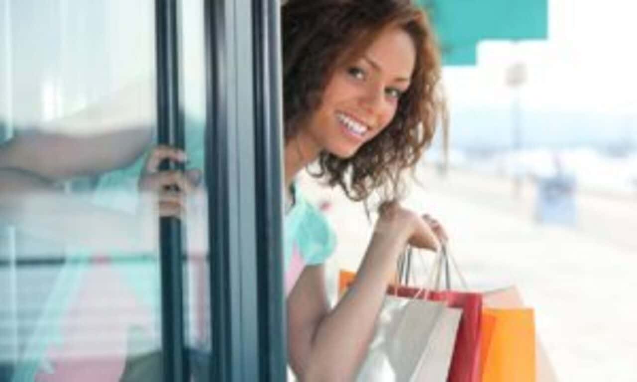 Mulher sorridente com sacolas de compra da mão
