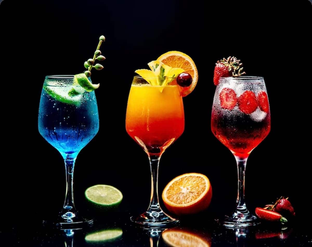 Taças com drinks. O da direita é vermelho, do centro é amarelo e o da esquerda é azul