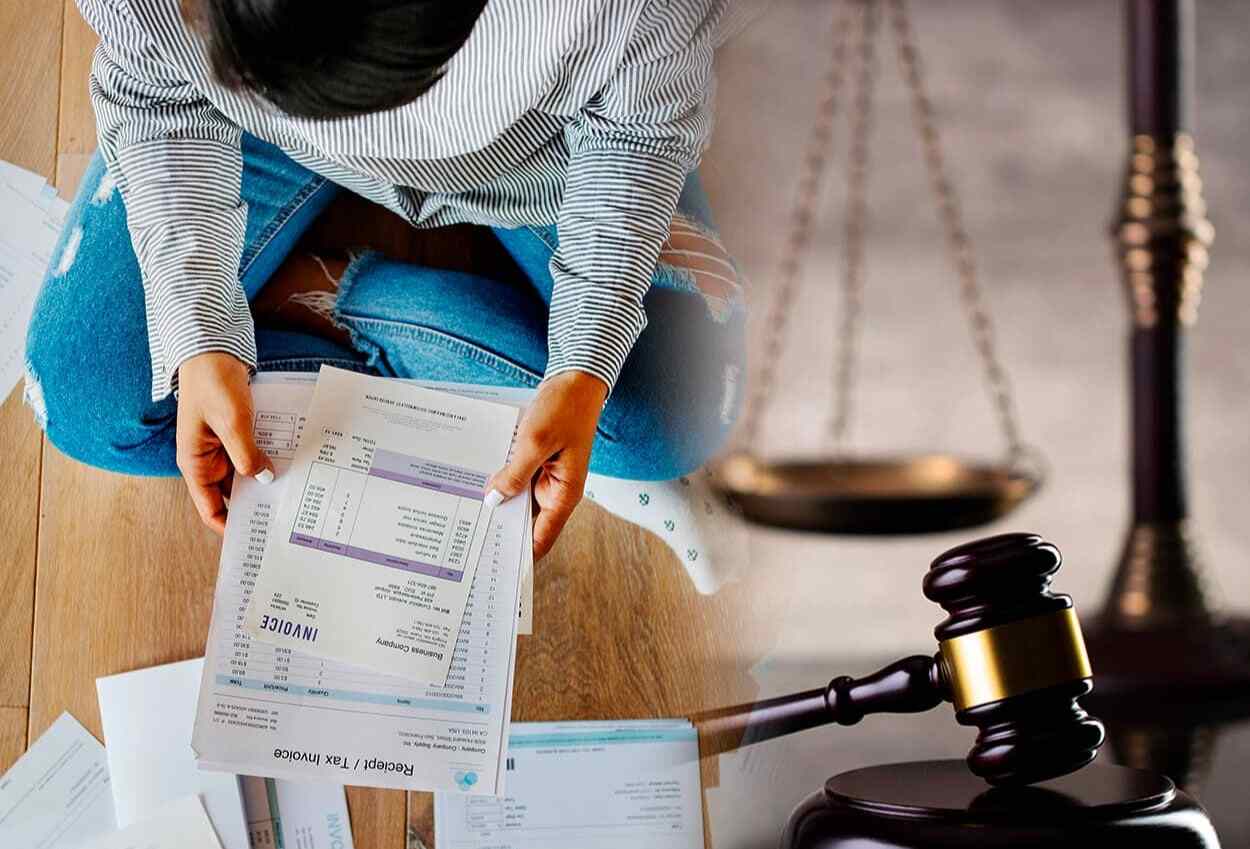 mulher segurando contas de dívidas e um martelo de tribunal ao lado