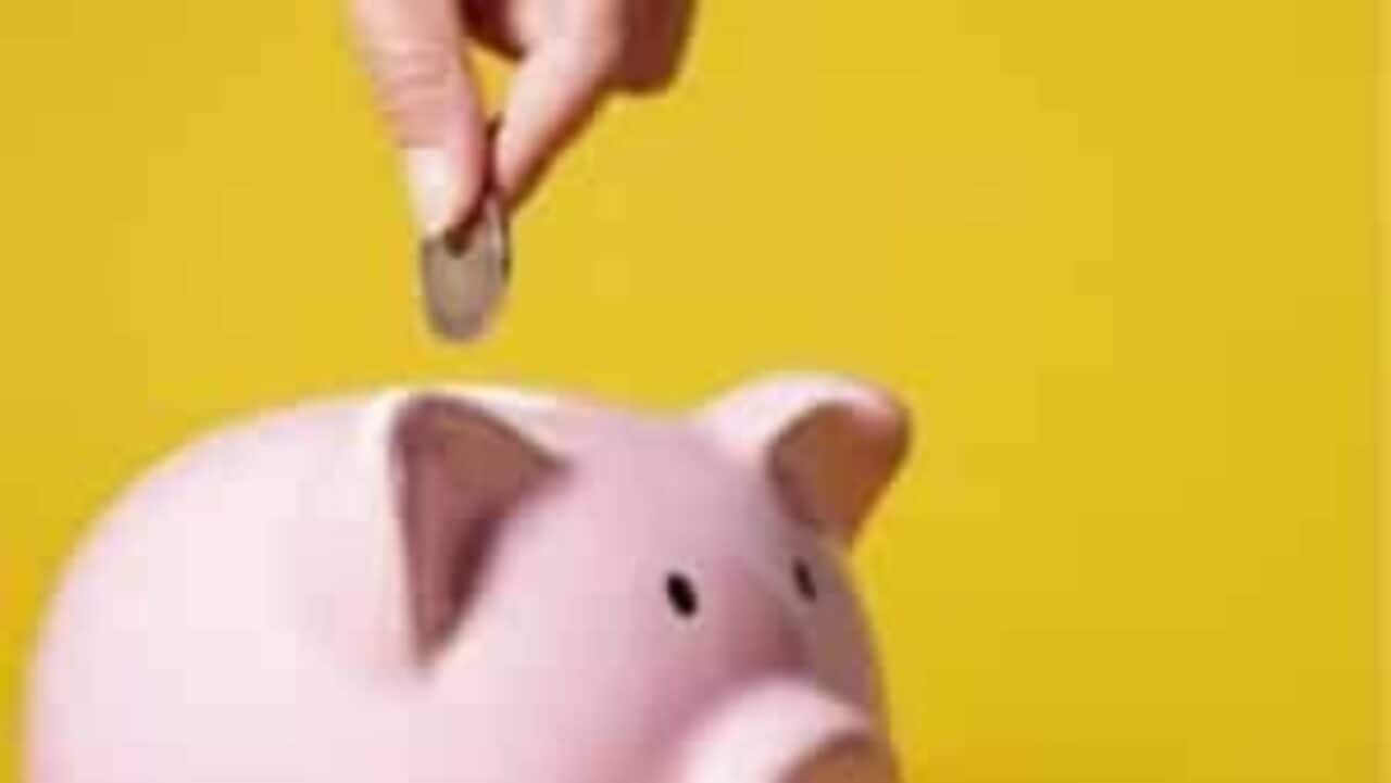 Pessoa colocando uma moeda de 1 real num porquinho de porcelana rosa inverno