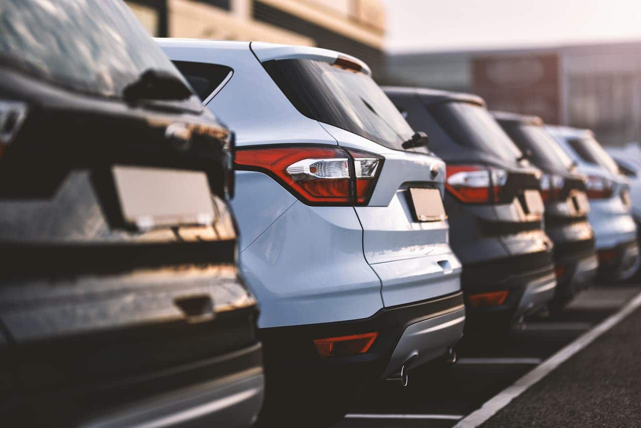 Fileira de um mesmo modelo de carro, mas em cores diferentes, lado a lado em um estacionamento. A imagem é da parte traseira e os carros não têm placas.