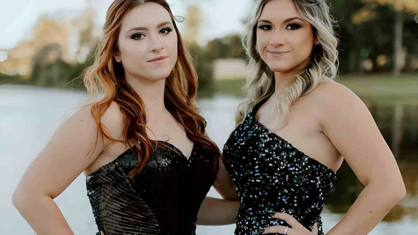 Duas mulheres posando lado a lado, com vestidos de luxo.