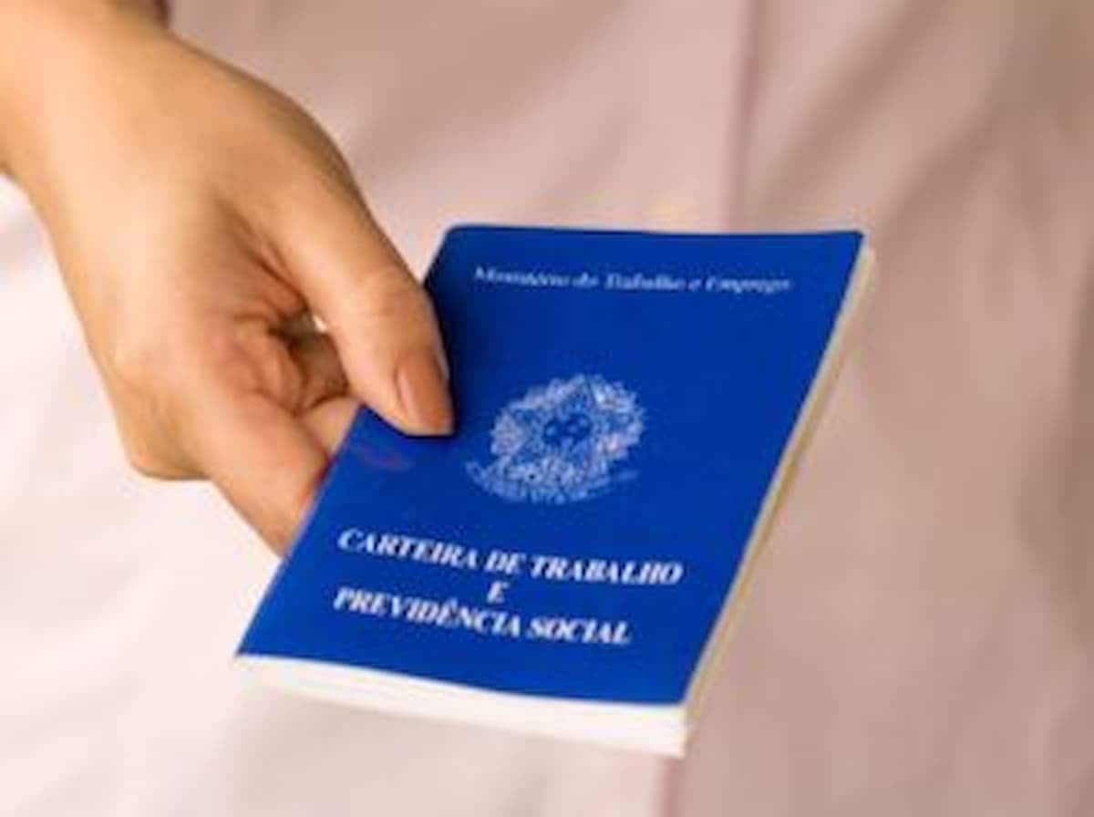 Mão feminina segurando uma Carteira de Trabalho