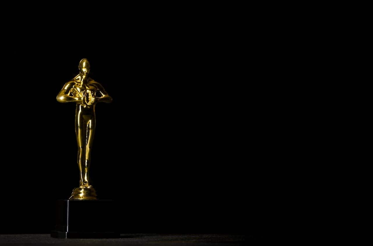 Estatueta do Oscar no canto esquerdo da imagem em fundo totalmente preto.