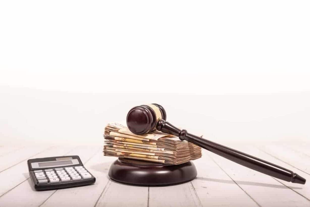 Calculadora, notas de dinheiro e martelo da justiça.