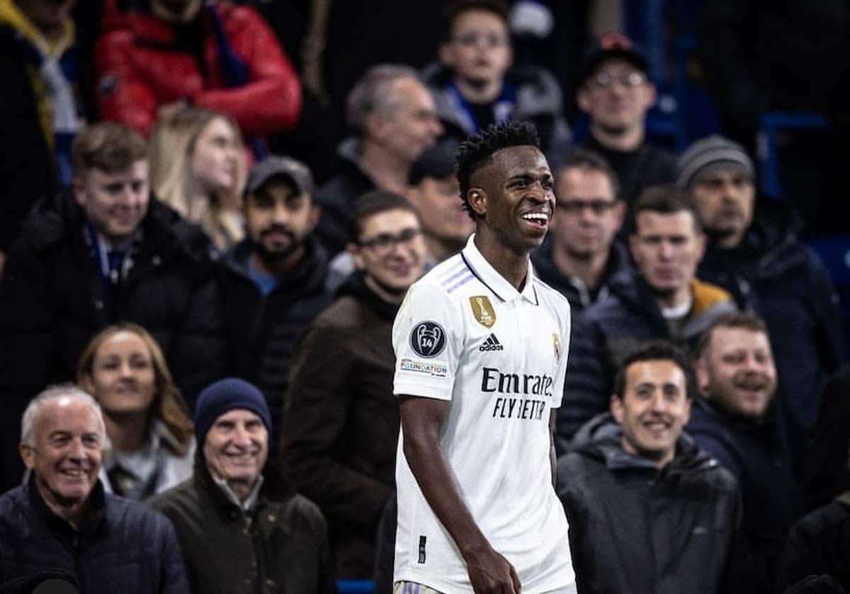Jogador Vinicius jr. sorrindo em campo com a camisa do real madrid