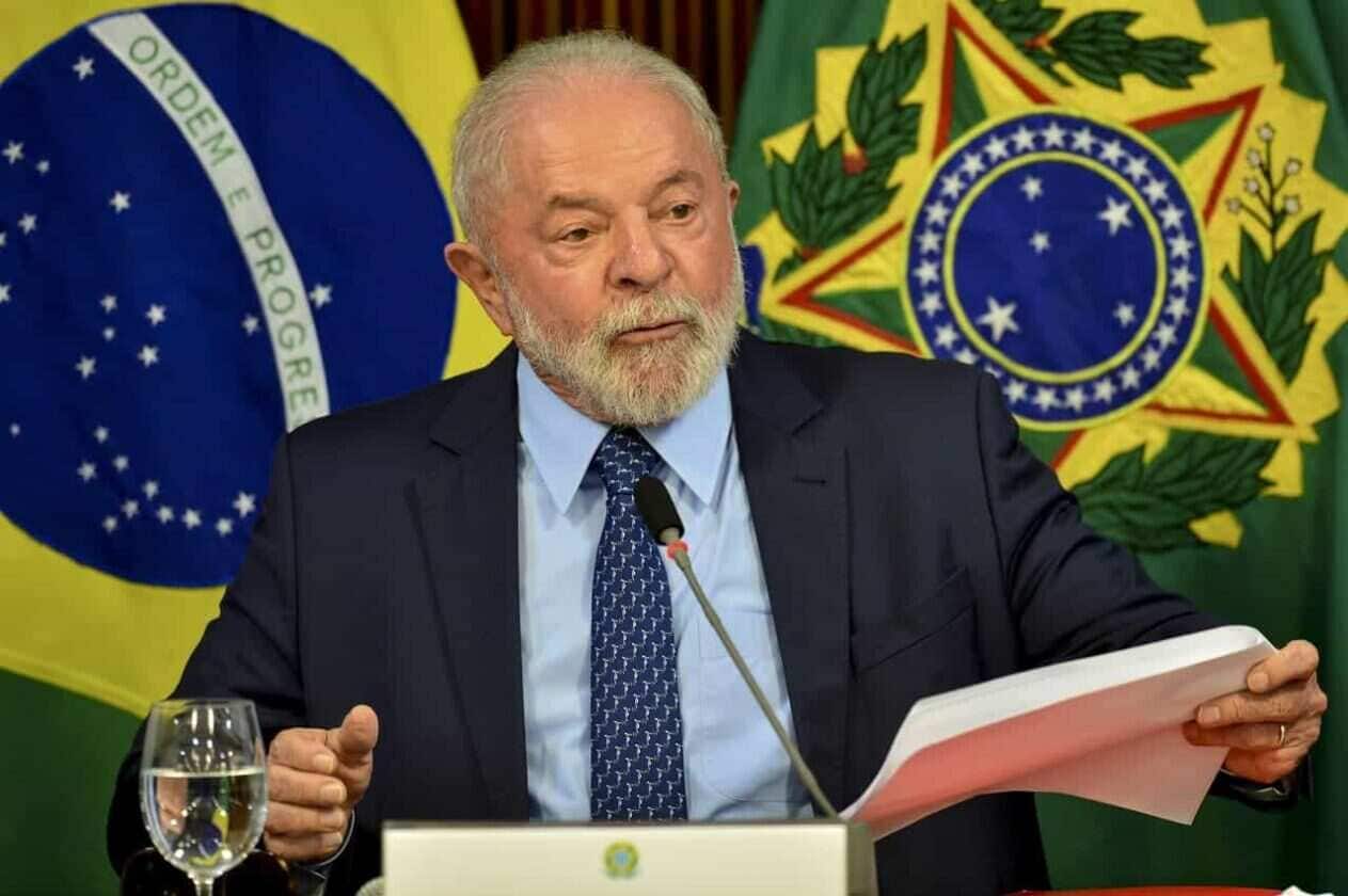 Presidente Lula discursando durante parlatório, com bandeira do Brasil ao fundo.