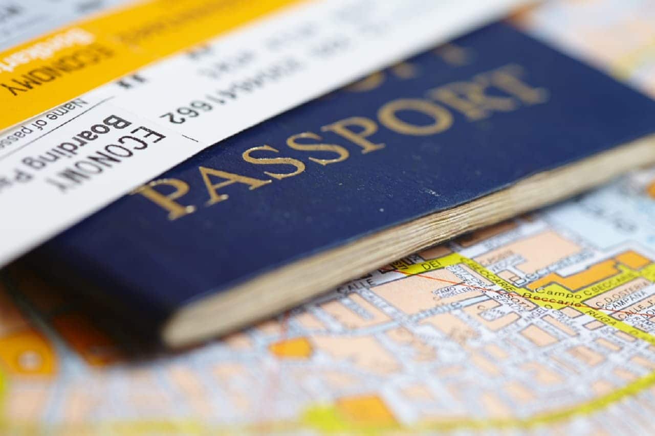 Imagem de um passaporte embaixo de uma passagem e em cima de um mapa