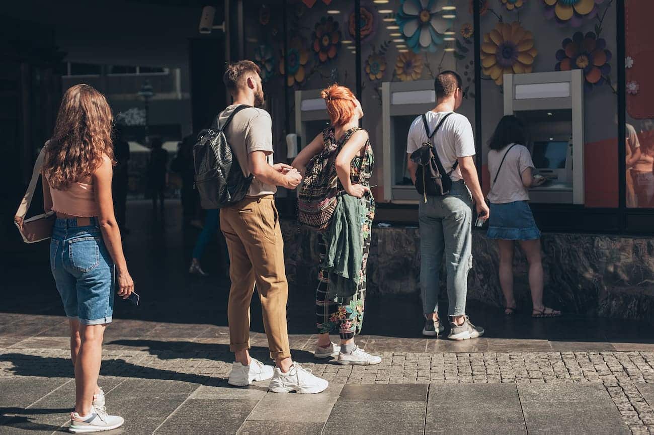Pessoas na fila de um caixa eletrônico.