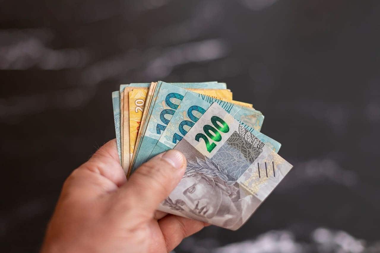Imagem de uma pessoa segurando notas de reais