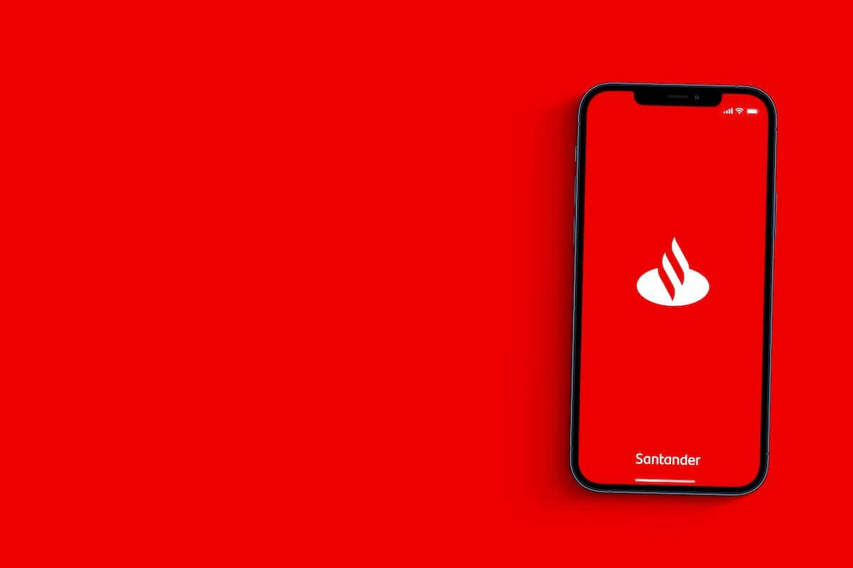 Aplicativo do Santander em celular sobre fundo vermelho