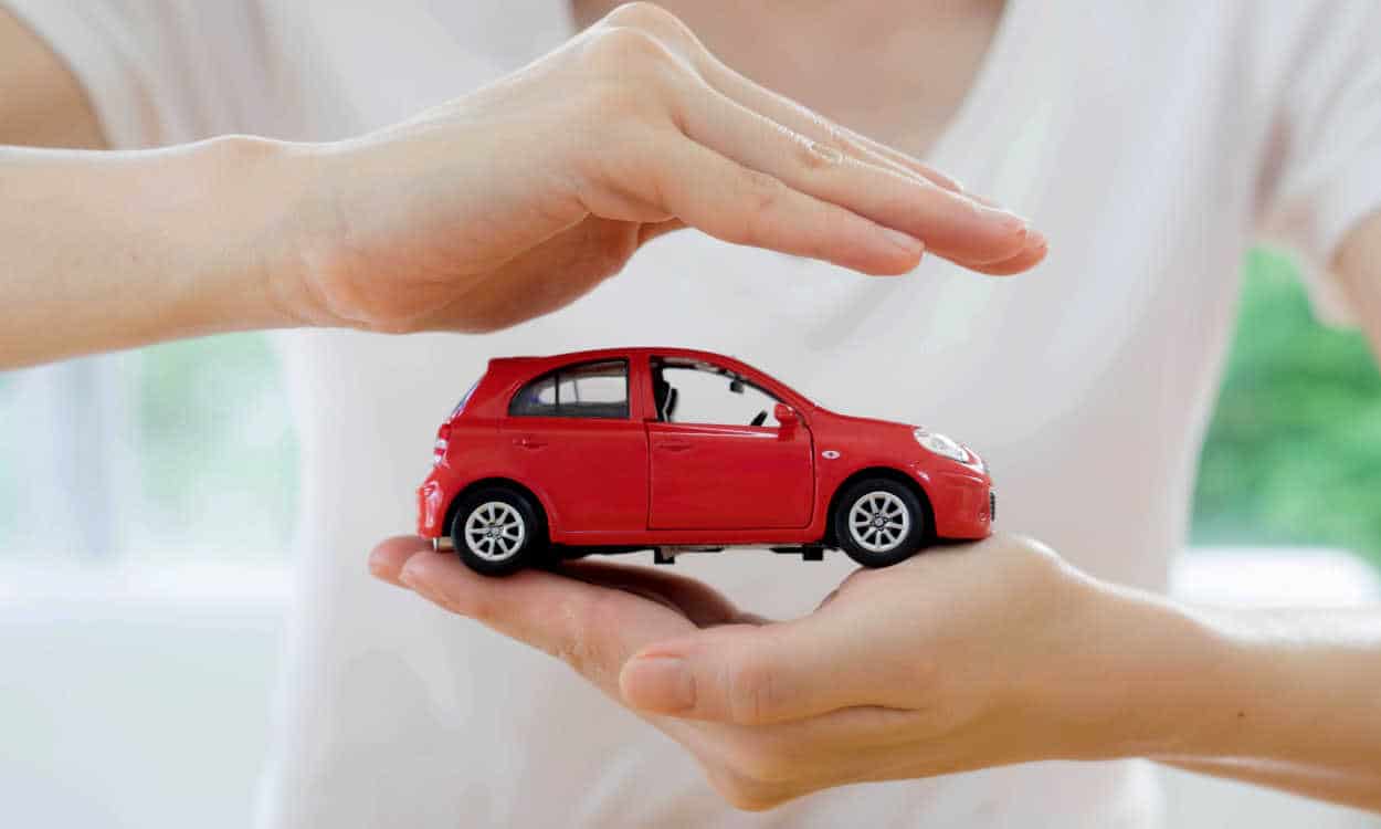 Pessoa usando as mãos para proteger a miniatura de um carro setor automotivo